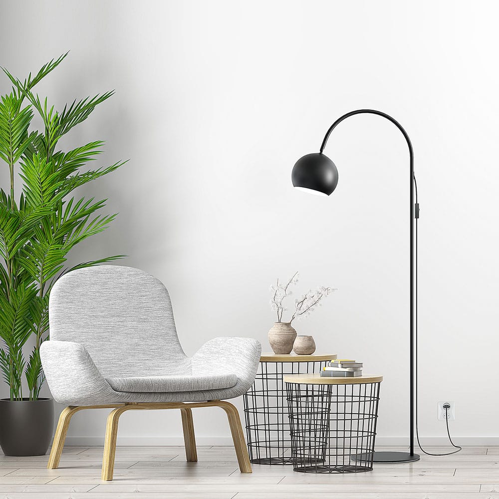 Valaisin Grönlund Round-lattiavalaisin. Miljöökuvassa valaisin vaaleanharmaan nojatuolin kanssa.