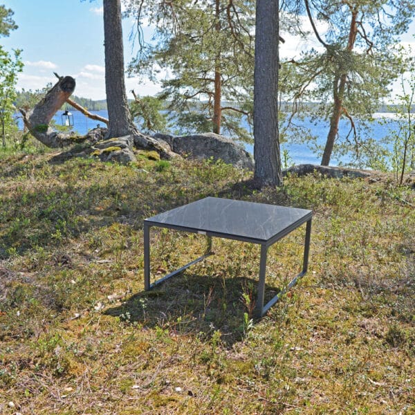 Brafab Talance-sohvapöytä ulos. Miljöökuvassa pöytä on kanervaisessa maisemassa, taustalla järvi.