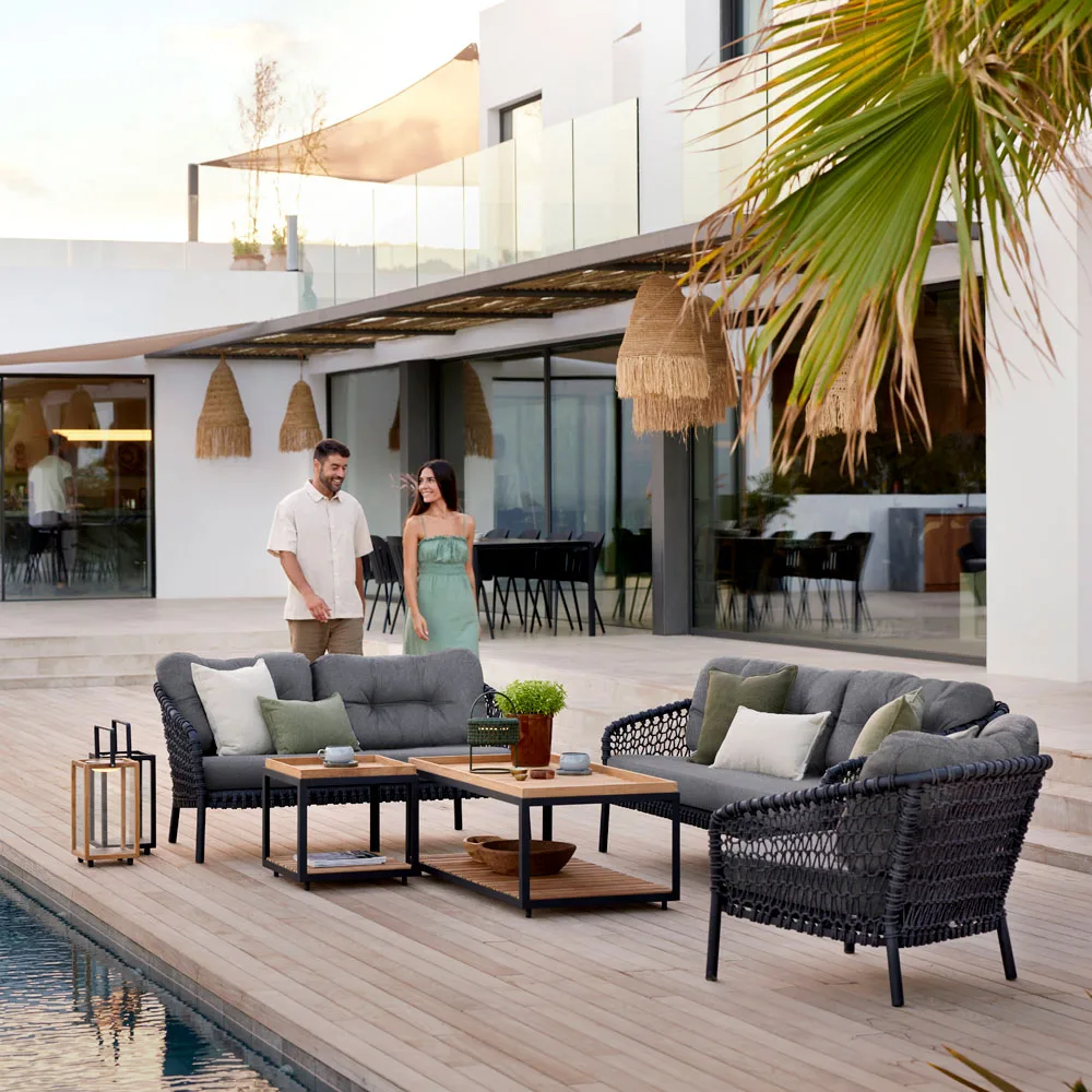 Cane-line Ocean-ulkosohva ja ulkonojatuoli, miljöökuvassa patio ja sohvien takana mies ja nainen
