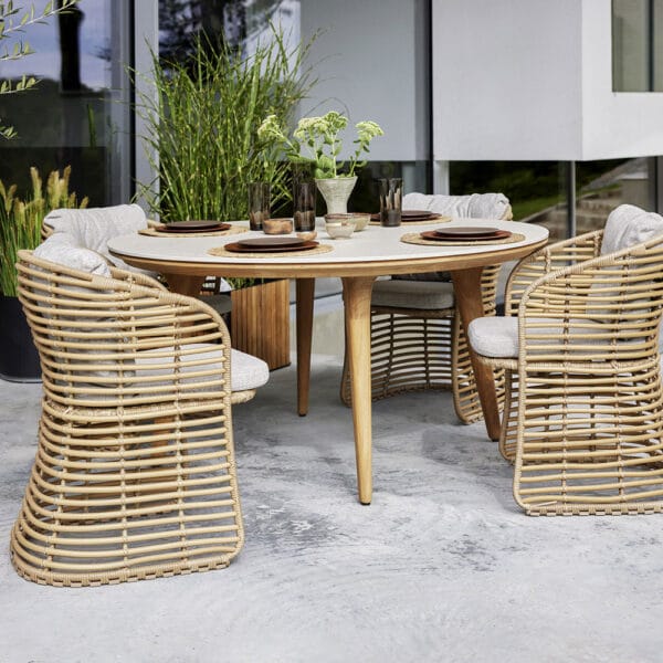 Cane-line Basket-ulkotuoli Weave-polyrottingista, vaalea tuoli, jossa taupen sävyinen pehmuste. Miljöökuvassa Aspect-pöydän kanssa.