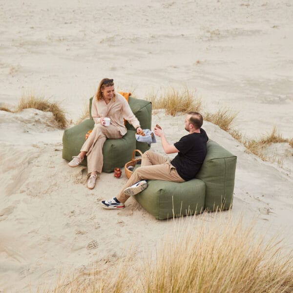 SACKit Soft Sofa -nojatuolit, miljöökuvassa mies ja nainen istuvat hiekkarannalla ja nojatuoleissa. Vihreä (olive) kangas.