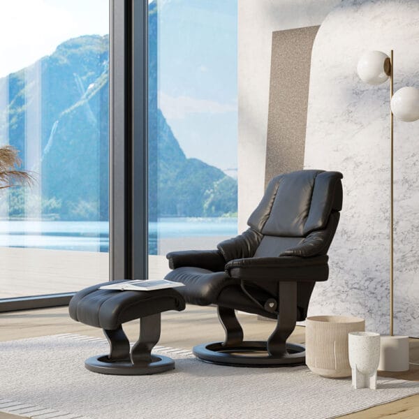 Stressless Reno-lepotuoli rahilla, musta nahka ja tumma puu. Miljöökuva.