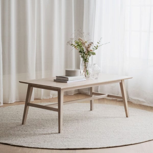 Rowico Filippa-sohvapöytä, suorakaide 130 cm, valkopesty fsc-tammi. Miljöökuvassa pöytä pyöreän villamaton päällä vaaleaseinäisessä huoneessa. Taustalla vaalea verho.