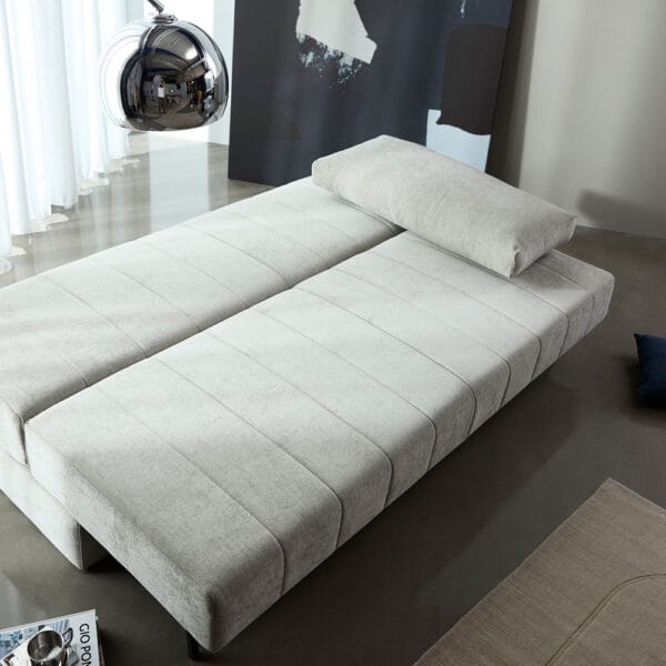 Innovation Living Akello-vuodesohva ilman käsinojia, vuodemekanismi. Vaalea Avella Sand 280 -kangasverhoilu. Miljöökuva.