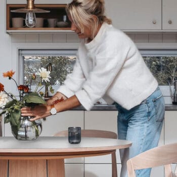 Artikkelikuva | Skovby #33-pöytä. Miljöökuvassa nainen asetteleen kukkia pöydälle.