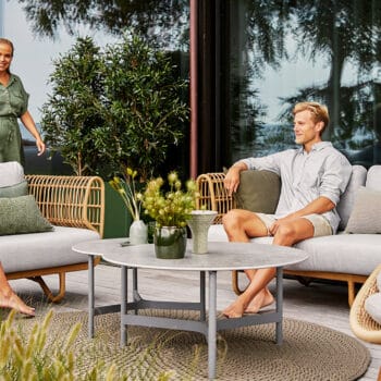 Artikkelikuva | Cane-line Nest-sarjan ulkosohva ja nojatuoli, Peacock-nojatuoli. Miljöökuva ihmisillä.